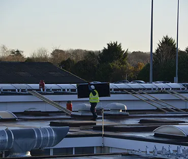 Worker carrying solar panel to be installed on the roof of the Engineering & Construction Centre